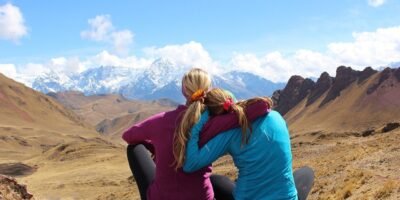 a mother and daughter rest in front of a snowy mountain on the ancascocha trail 7 days